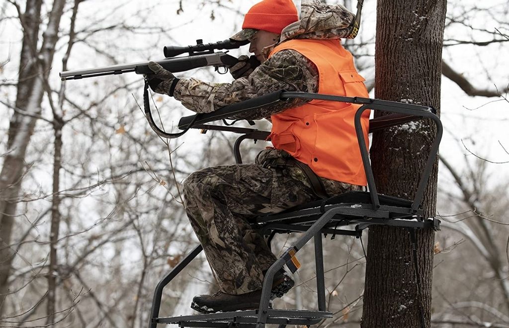 A hunter sits on a two-man ladder stand and is ready to shoot