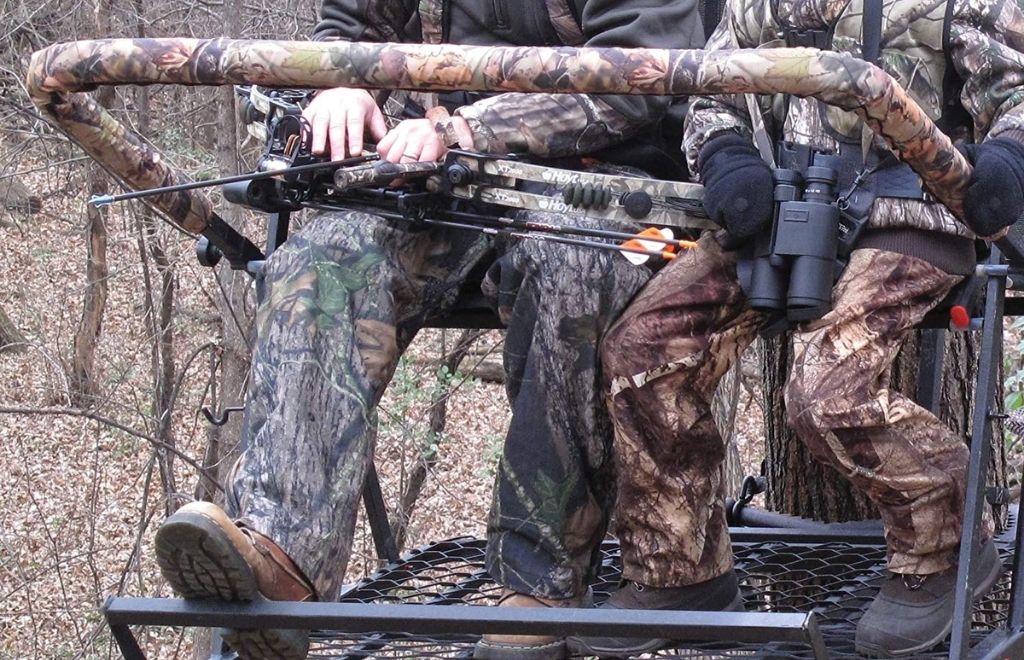 There's a man and a kid sitting on the ladder treestand