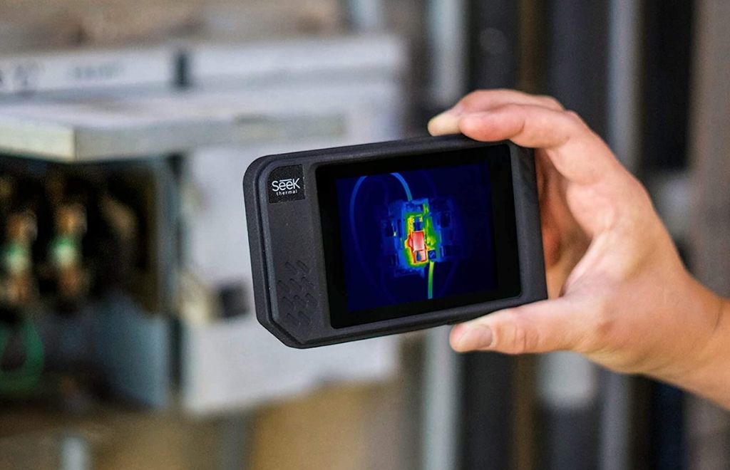 A man holds a thermal imaging camera in his hand