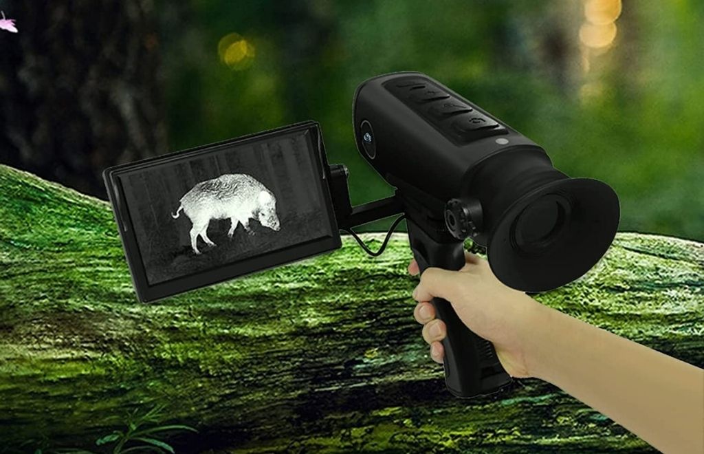A hand is holding a hunting thermal scope camera in the jungle