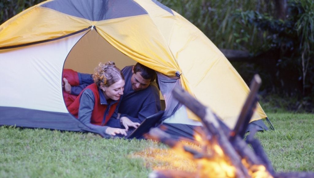 A couple using a laptop while camping
